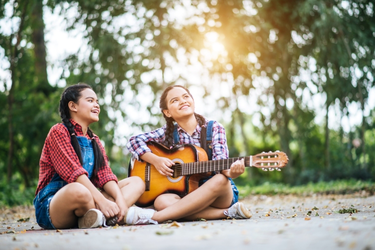 Two girl relax playing guitar and sing a song